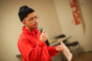 Senior AmeriCorps Member Avian Soto speaking into a microphone wearing the iconic City Year full zip jacket.