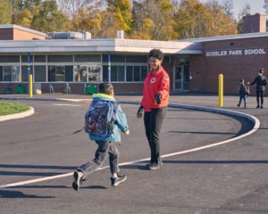 MaDeja Leverett greets students as they run in to school