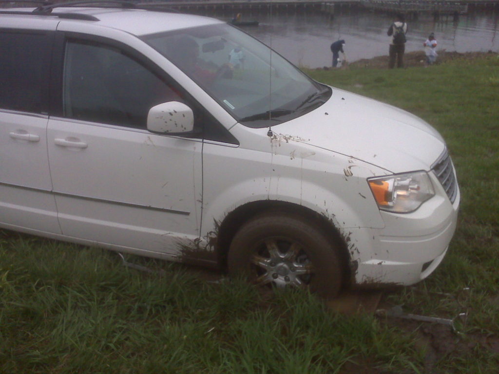 White van gets stuck in the mud.