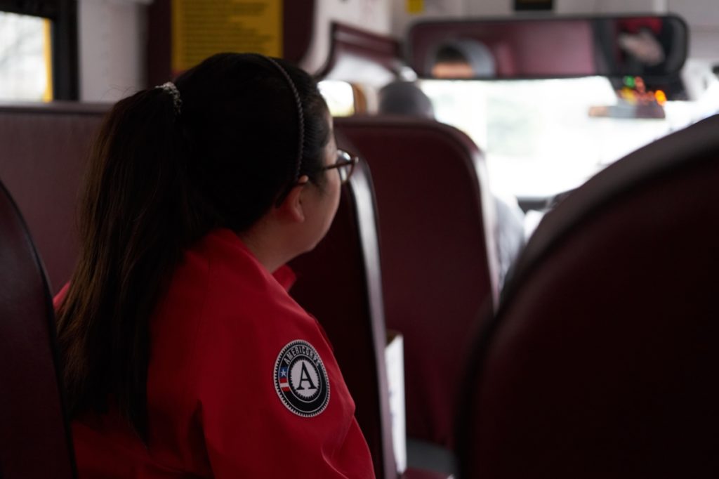 Elaine Lunsford waits on a bus while traveling through Manchester to deliver homework and food.