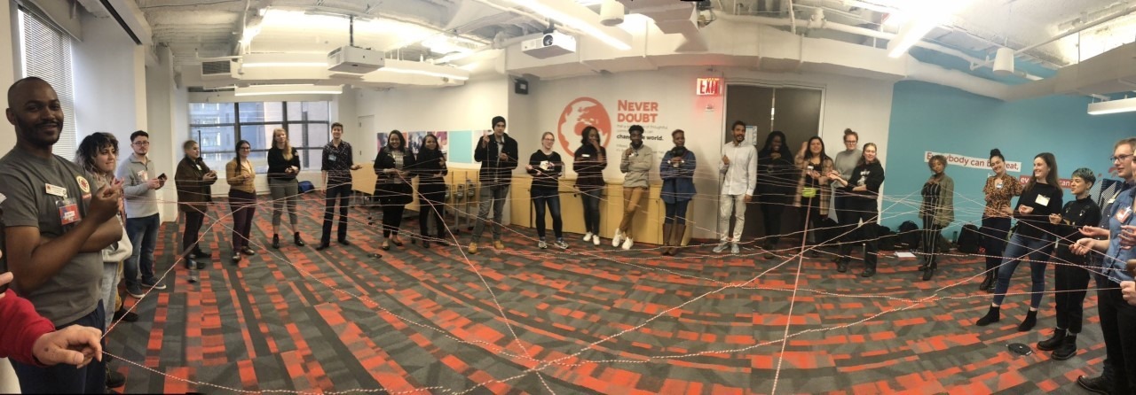 Civic Engagement members stand in a circle and hold string that forms a twisted web to illustrate the connections formed.