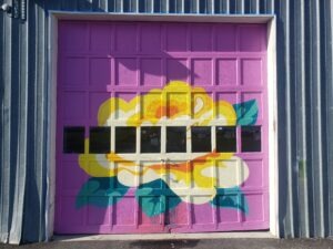 A garage door painted with a flower is shown. 