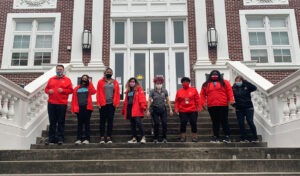 The City Year tam at ARISE Academy stands on the front steps of the school in their striking City Year red jackets