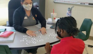 A City Year AmeriCorps member works with a student on letter recognition skills