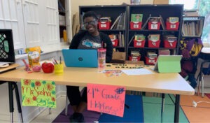 A City Year AmeriCorps members sits at her command center to support distance learning, bringing joy and enthusiasm