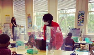 AmeriCorps member supports in a classroom with students with masks and dividers