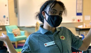 A City Year AmeriCorps member gestures to her empty middle school classroom proudly