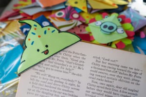 a bookmark shaped like a green ice cream cone holds open a copy of Chitty-Chitty-Bang-Bang. Other colorful bookmarks are spread out in the backround