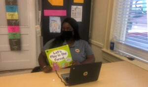 AmeriCorps member Samantha Richard poses in the classroom with a book she plans to read to her first grade students.