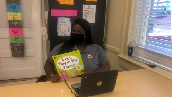 AmeriCorps member Samantha Richard poses in the classroom with a book she plans to read to her first grade students.