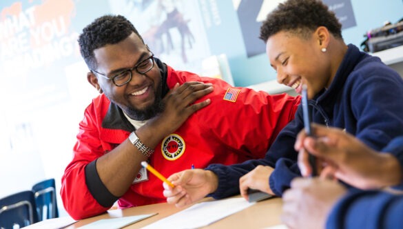 City Year AmeriCorps member smiling with student in school