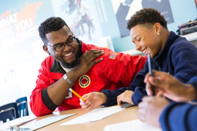 City Year AmeriCorps member smiling with student in school
