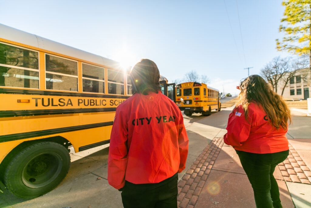 Two City Year Tulsa AmeriCorps members prepare to greet students as the buses arrive