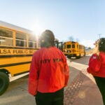 Two City Year Tulsa AmeriCorps members prepare to greet students as the buses arrive