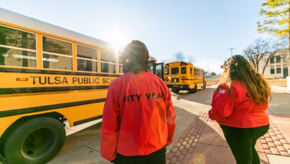 Two City Year Tulsa AmeriCorps members prepare to greet students as the buses arrive