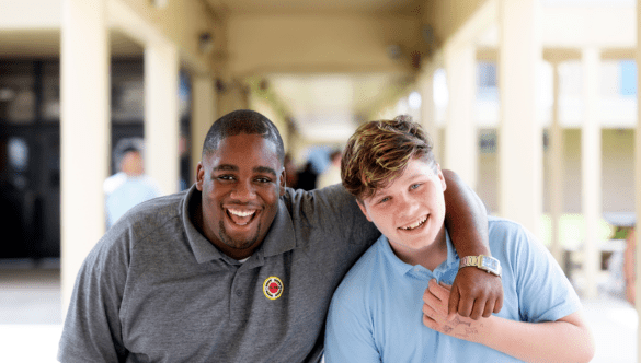 An AmeriCorps member smiles at the camera with a student.