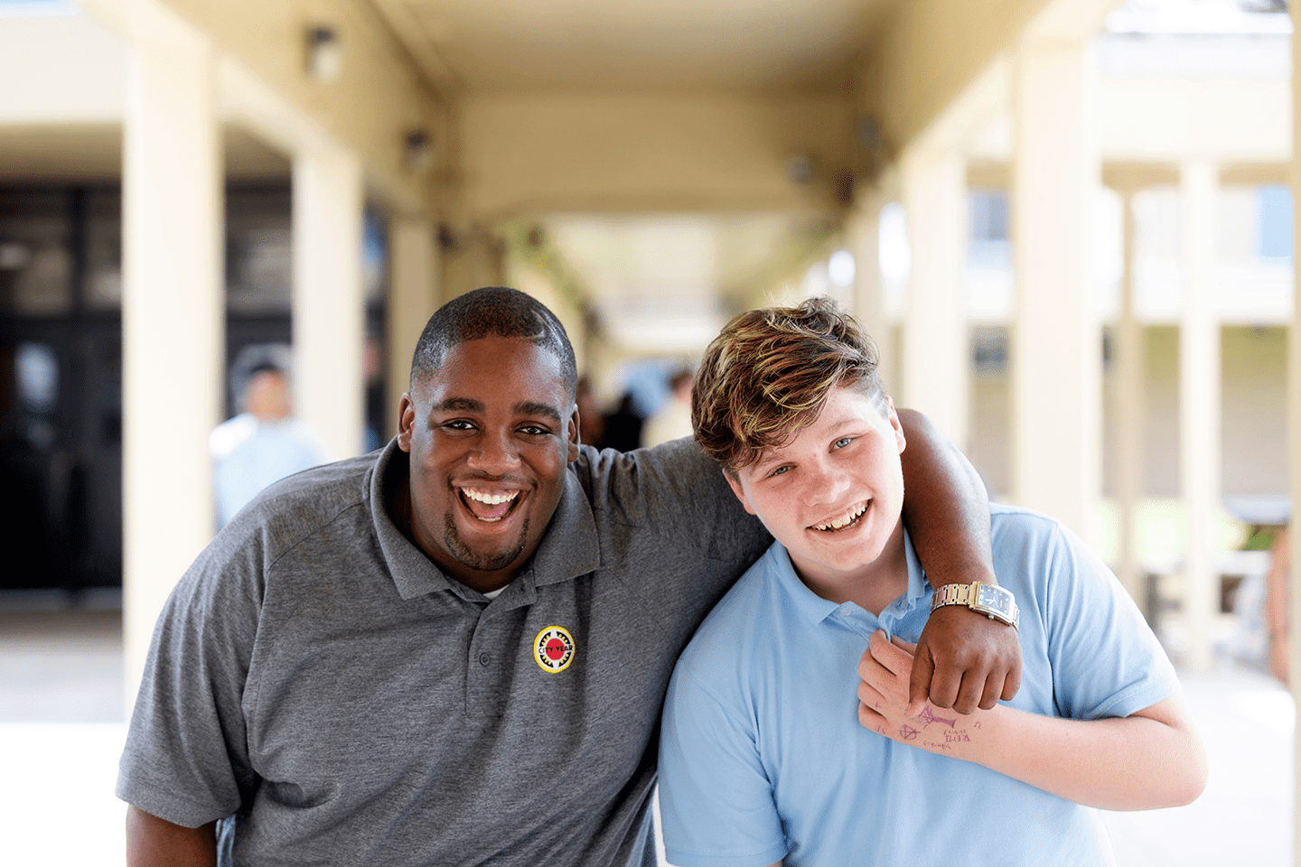 A City Year AmeriCorps member smiles at the camera with a student.