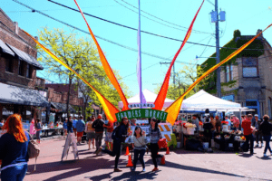 clusters of people stand a different tables and vendors at the Ballard Farmers Market in Seattle