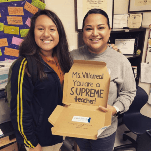 A teacher holding their appreciation gift and standing with a student