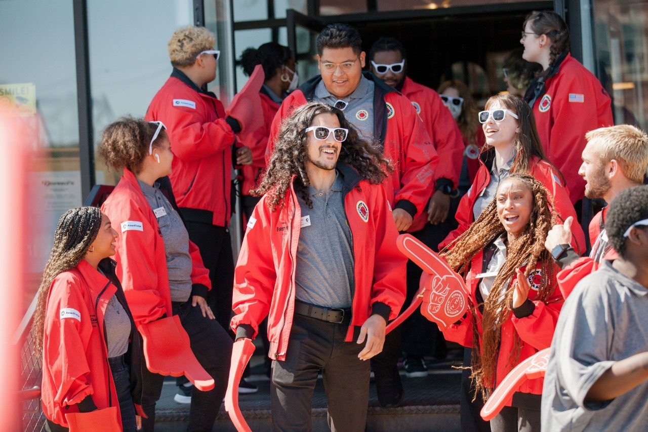 AmeriCorps members in their red jackets form a spirit line for corps members exiting a building