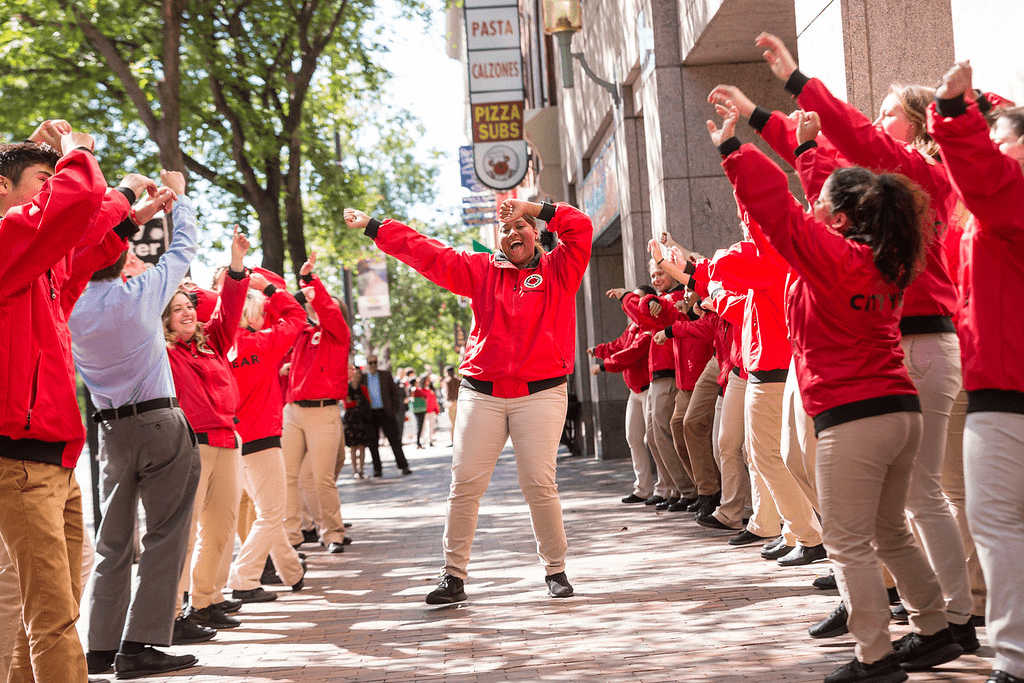 A City Year AmeriCorps member dances in between two rows of corps members cheering them on