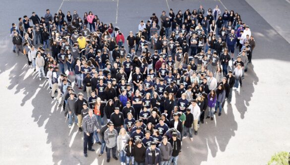 a large group of students a teachers standing in the shape of a filled heart