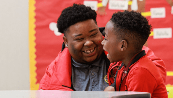 an elementary student and City Year AmeriCorps member laughing together