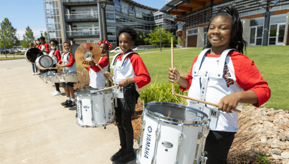 a line of students plays the drums and cymbals