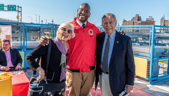 City Year Buffalo Executive Director Michael Stevens stands smiling with two individuals