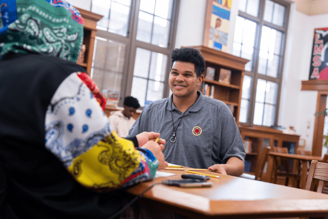 City year Columbus AmeriCorps member smiles at a student wearing a hoodie