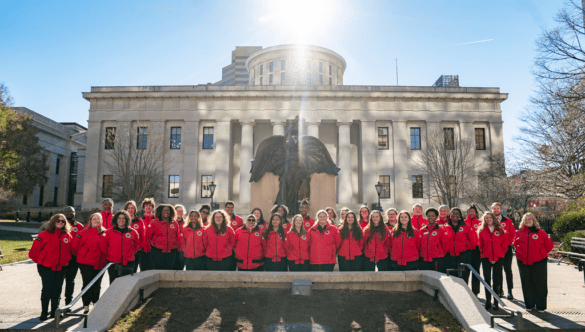 Two rows of City Year Columbus AmeriCorps members smile in front of the state house