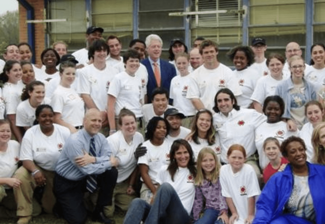 a group of City Year AmeriCorps members smiling with Bill Clinton