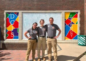 Three City Year members in front of a mural