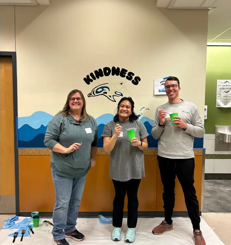 Three volunteers standing in front of a completed 